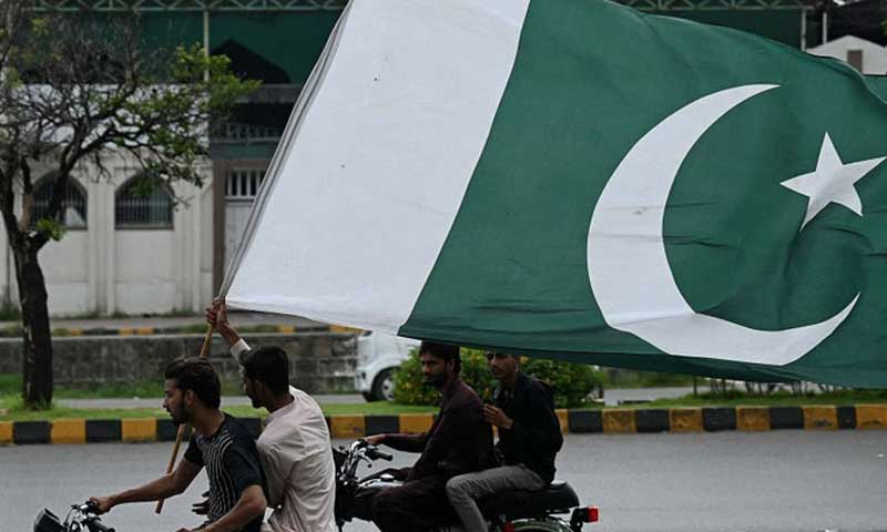 A pillion rider waves Pakistani flag