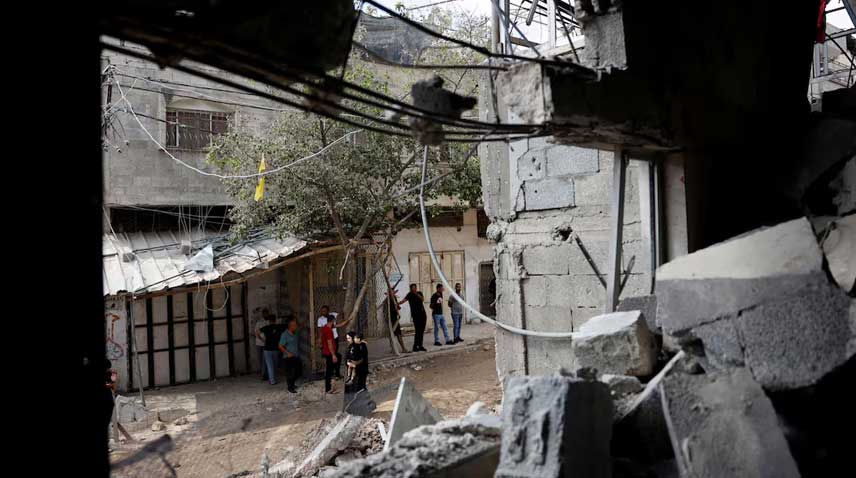 Palestinians stand near a damaged house following an Israeli military raid in Tulkarm in the Israeli-occupied West Bank