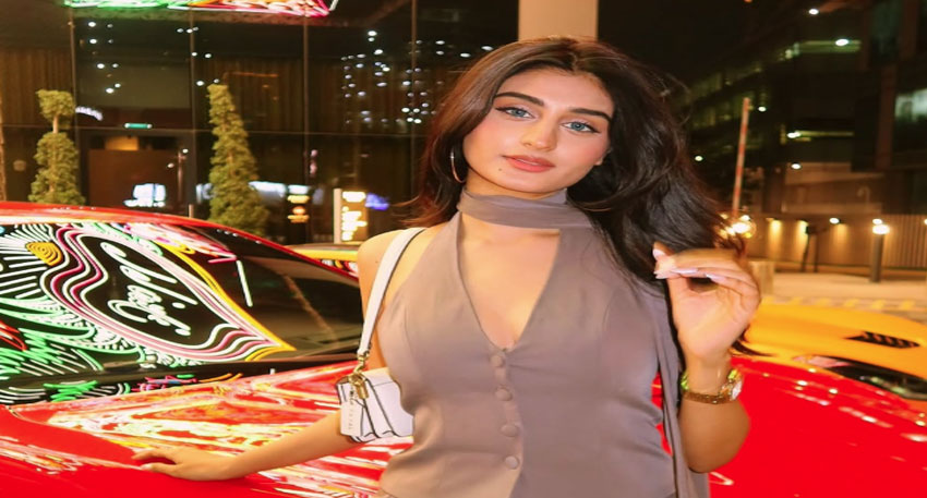 Payal Gaming posing with a vibrant red sports car at night.