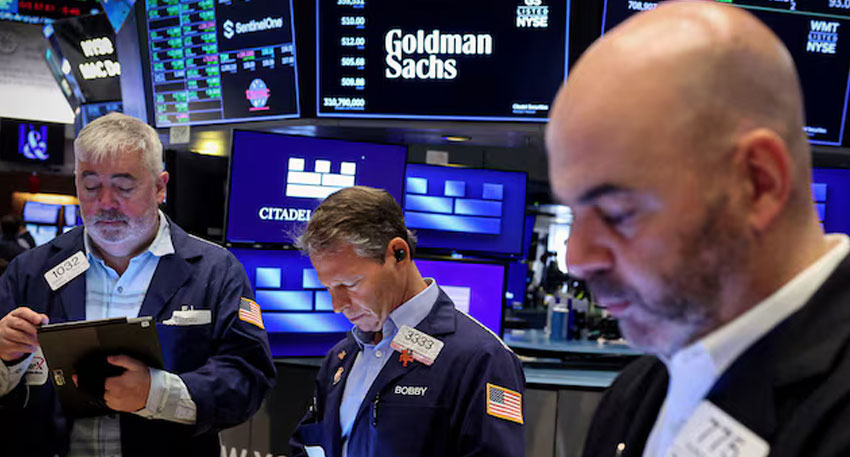 Traders work on the floor, as a screen displays The Goldman Sachs logo and trading information, at the New York Stock Exchange (NYSE) in New York City, U.S., April 14, 2025. Reuters