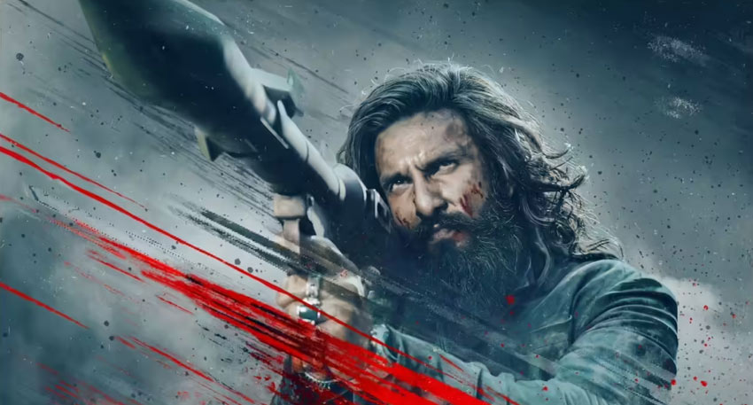 Ranveer Singh with long hair and a beard, aiming a rocket launcher in a scene from the film Dhurandhar 2.