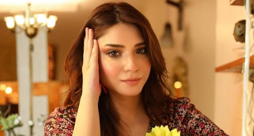 Pakistani actress Ramsha Khan posing in a floral outfit with a yellow flower.
