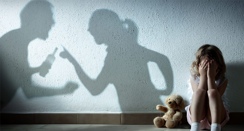 A child hides in fear, reflecting the silent impact of domestic violence on young minds.