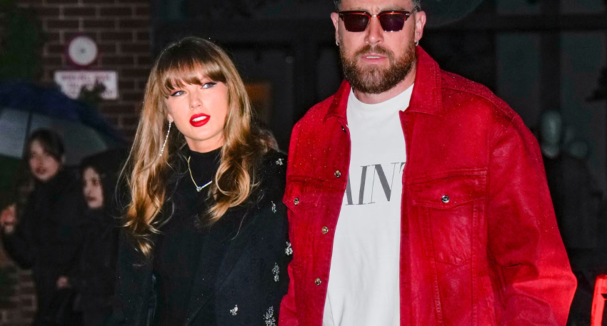 Taylor Swift and Travis Kelce walking together outdoors, Swift in a black coat and Kelce in a bright red jacket.