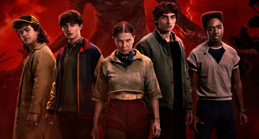 Cast of Stranger Things Season 5 posing together against an ominous red background.