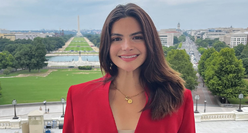 Valentina Gomez in a red blazer, smiling in front of the National Mall in Washington, D.C.