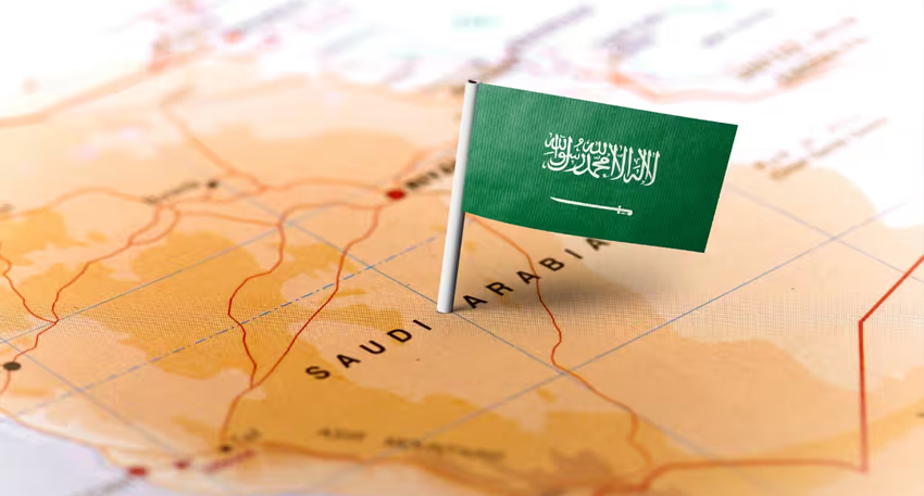 Small Saudi Arabian flag pin placed on a map over the text Saudi Arabia.