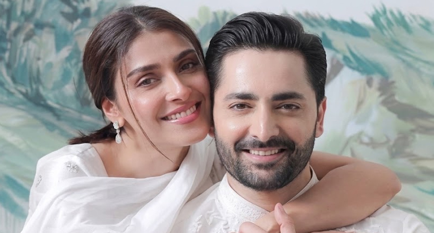 Pakistani actors Ayeza Khan and Danish Taimoor smiling together in white outfits.