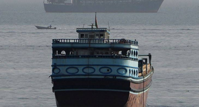 Large blue and brown traditional dhow boat floating on calm ocean water.