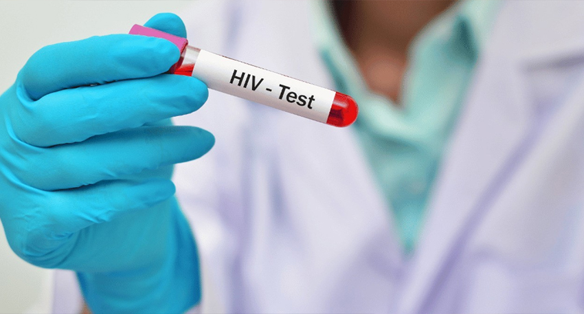 Gloved hand holding an HIV test blood tube.