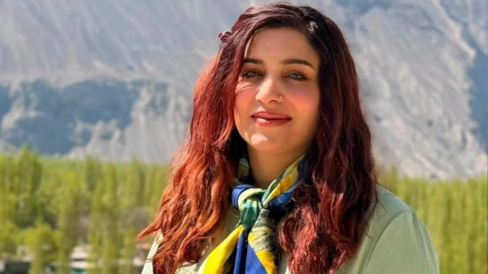 Pakistani mountaineer Asma Mushtaq smiling in front of mountains.