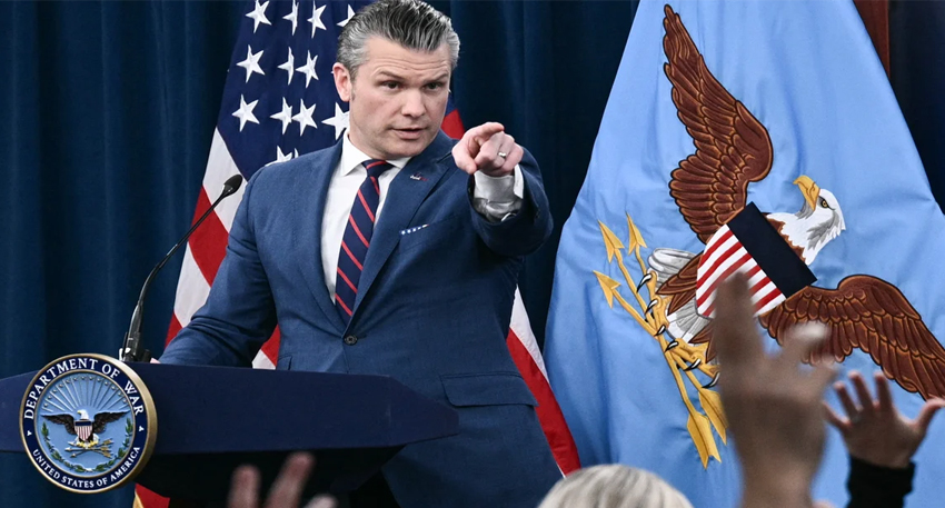 Pete Hegseth points from a podium with the Department of War seal and US flags behind him.