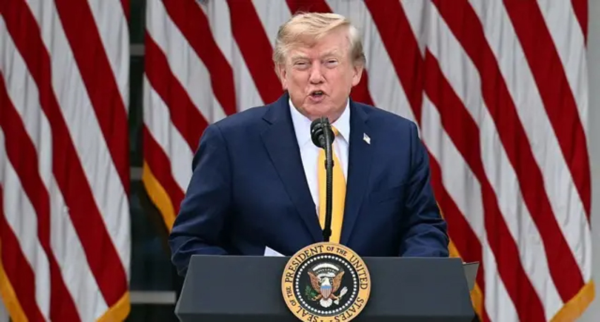 Donald Trump speaking at a podium with US flags background.