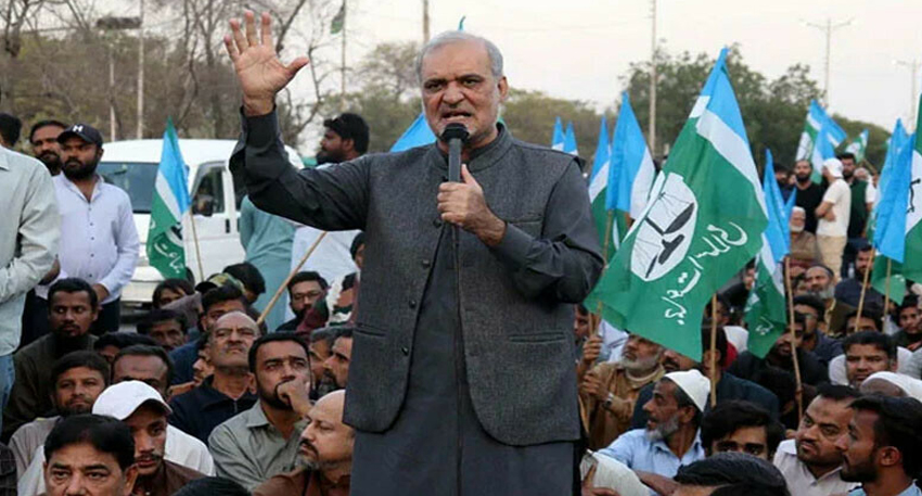 JI chief Hafiz Naeem ur Rehman addresses a crowd holding flags.