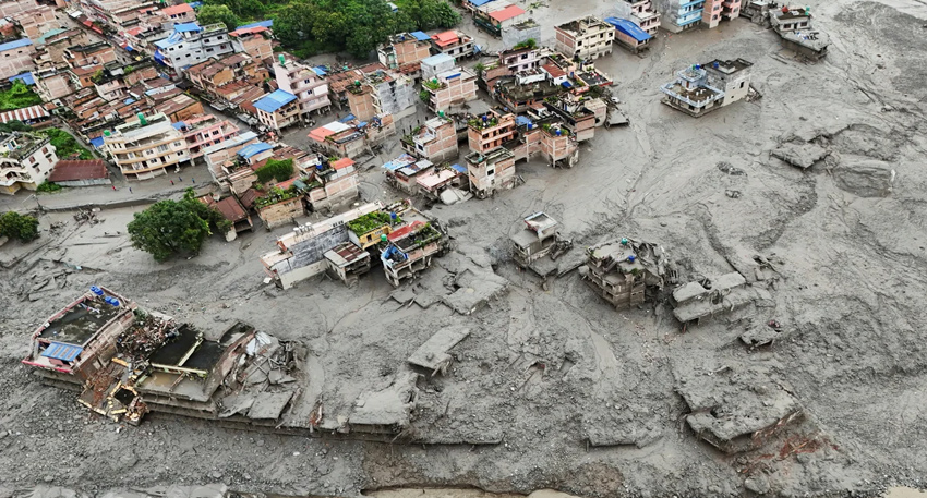 Aerial view of a coastal town destroyed by a massive gray mudslide and flash floods in Nepal.