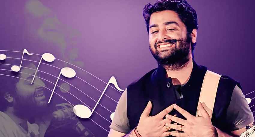 Arijit Singh smiling with his eyes closed, wearing a black vest and guitar strap against a purple background.