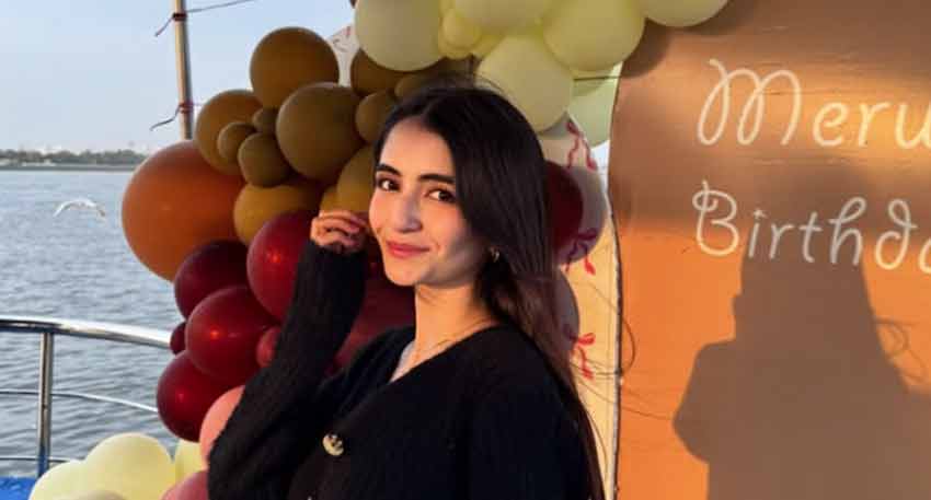 Merub Ali smiles for a photo during her birthday celebration surrounded by balloons and water in the background.