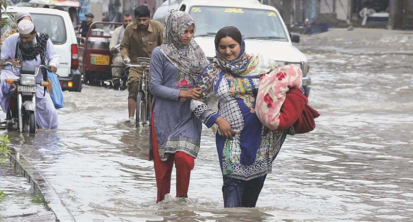 People walking through a flooded street after heavy rains in Lahore