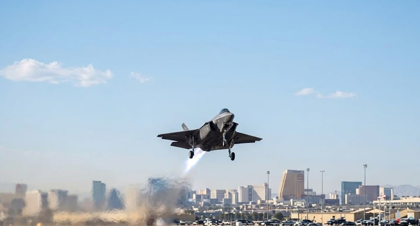 An F-35 fighter jet takes off from an airfield with the Las Vegas skyline visible in the background.