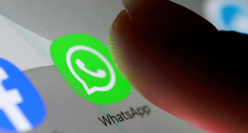 Hand tapping WhatsApp icon on smartphone screen.