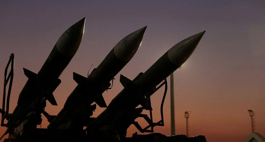 Three military missiles angled upward against a dark sunset sky.