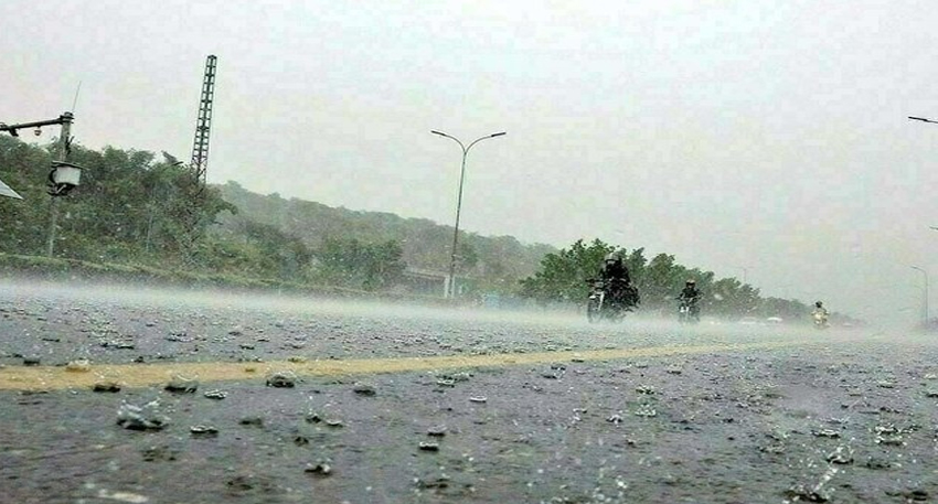 Vehicles driving on a flooded road during heavy monsoon rain.