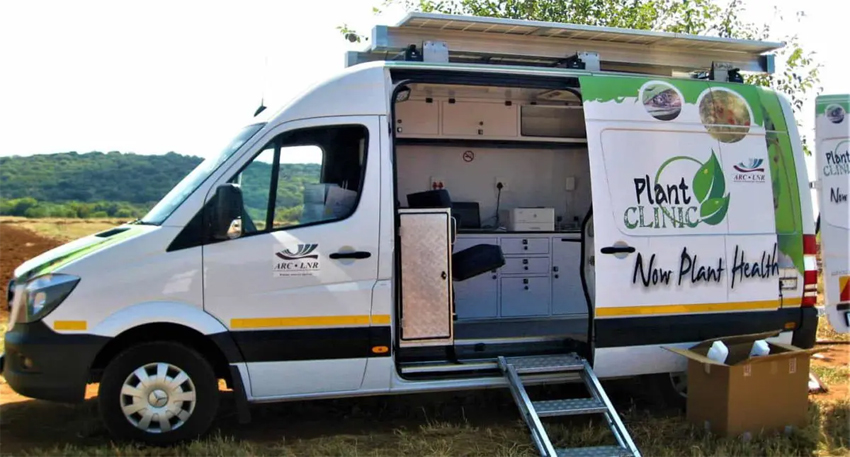 White mobile plant clinic van with open side door showing internal lab equipment.