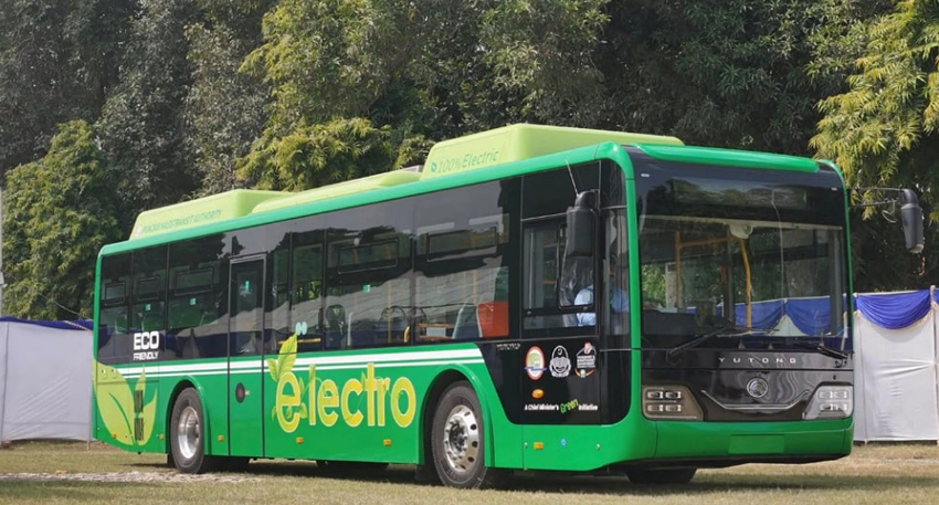 Green and black Yutong electric bus parked on grass.