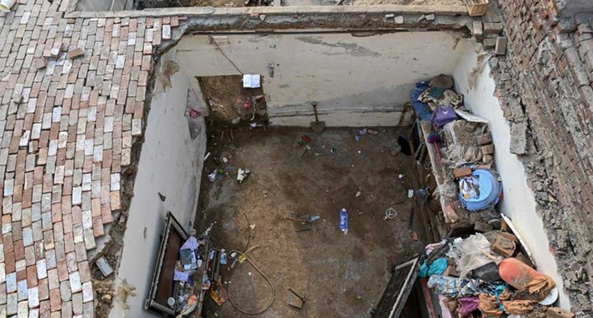 Top view of a house in Lahore with its brick roof completely collapsed, exposing debris inside the room.