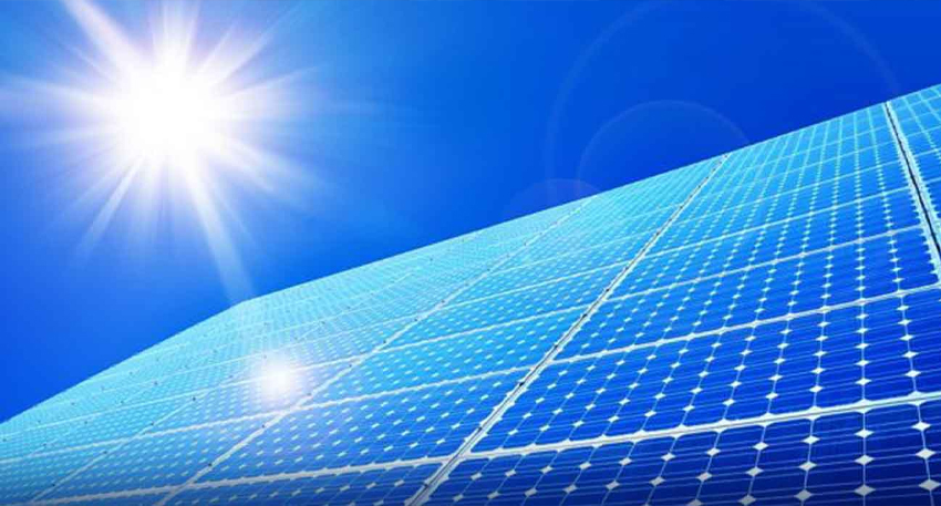 Solar panels angled toward a bright sun under a clear blue sky in Pakistan.