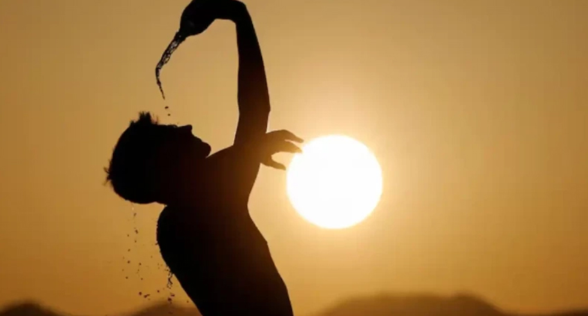 Alt Text: Silhouette of a person pouring water over themselves against a bright sun.