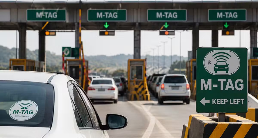 Cars passing through an M-Tag toll plaza in Pakistan with green M-Tag signage.