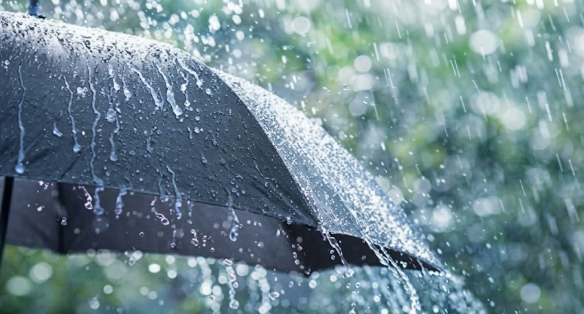 Black umbrella pelted by heavy rain and splashing droplets during a severe storm.
