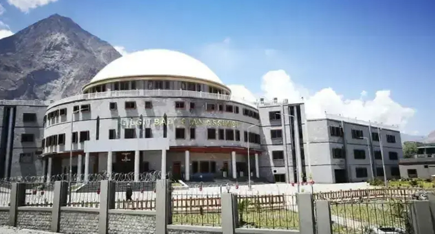 A large, modern stone building with a prominent white dome, identified as the Gilgit-Baltistan Assembly.