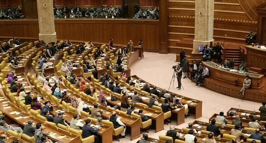 A wide shot of the Punjab Assembly in session with lawmakers seated in tiered, curved rows.