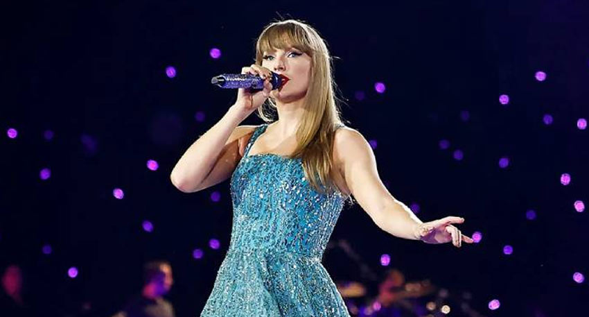 Taylor Swift performing in a sparkling blue dress, holding a purple microphone during her Eras Tour.
