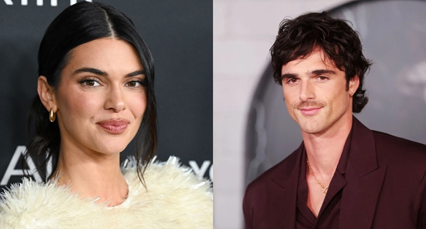 Kendall Jenner in a white feathered top next to Jacob Elordi in a maroon suit and gold chain.