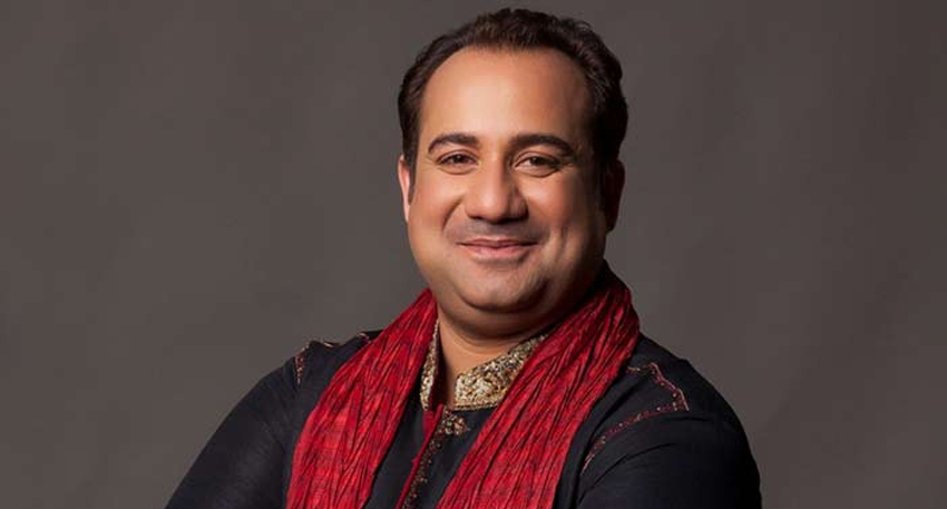 Pakistani singer Rahat Fateh Ali Khan smiling in a black and gold embroidered sherwani with a red scarf.