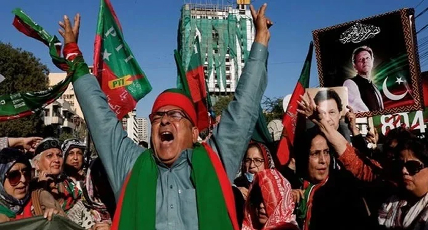 PTI supporters waving flags and shouting during a street protest in Pakistan.