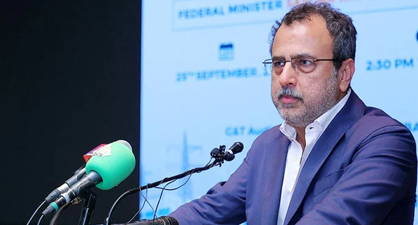 Awais Leghari speaking at a podium with microphones.