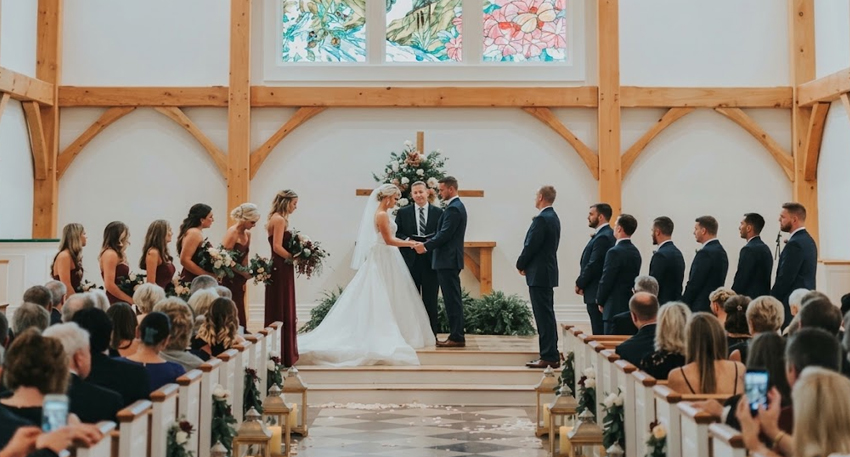 Wedding ceremony inside a church with a bride, groom, and wedding party at the altar.