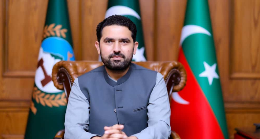 Sohail Afridi sitting in a chair in front of Pakistani flags.