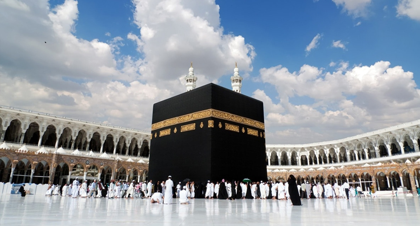 The Kaaba in Mecca's Grand Mosque under a cloudy sky.