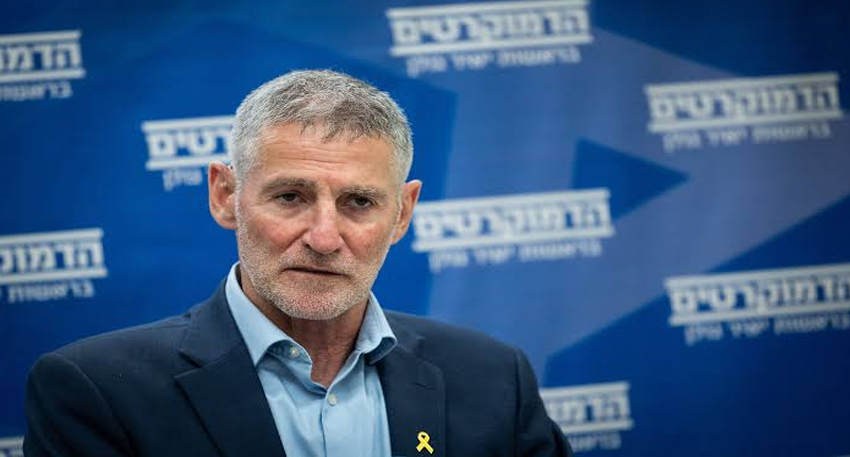 Israeli politician Yair Golan speaking at a press conference against a blue backdrop.