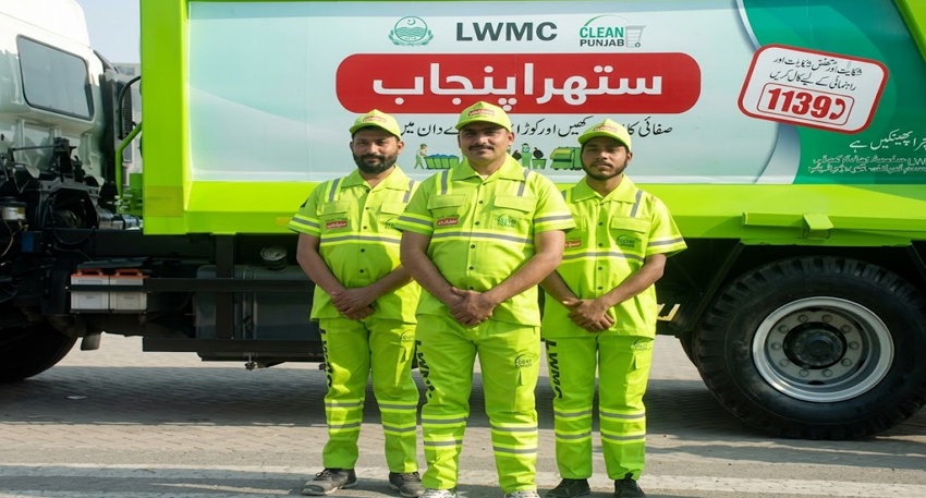Three sanitary workers in green uniforms stand in front of an LWMC Suthra Punjab waste collection truck.