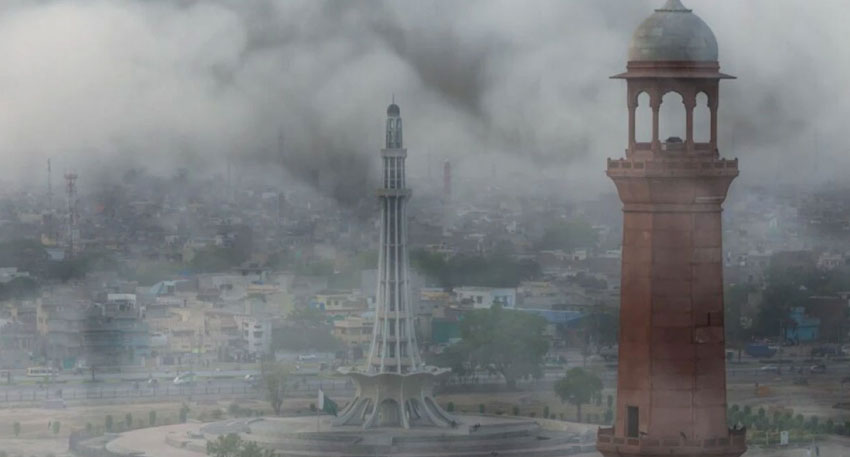 Minar-e-Pakistan and Badshahi Mosque minaret shrouded in heavy, dark smog in Lahore.