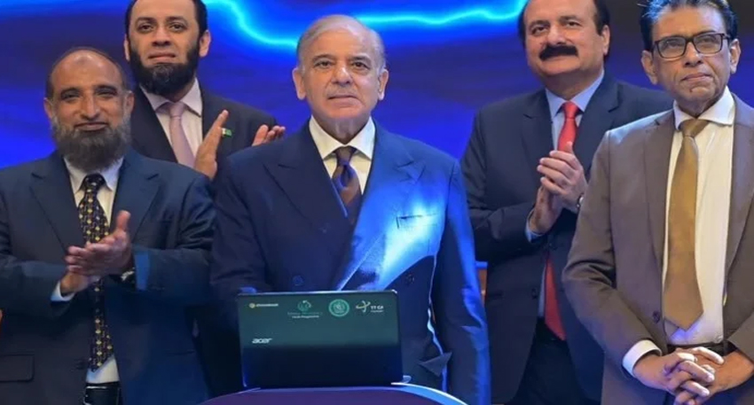 PM Shehbaz Sharif stands with officials behind a laptop launching a Chromebook distribution scheme.