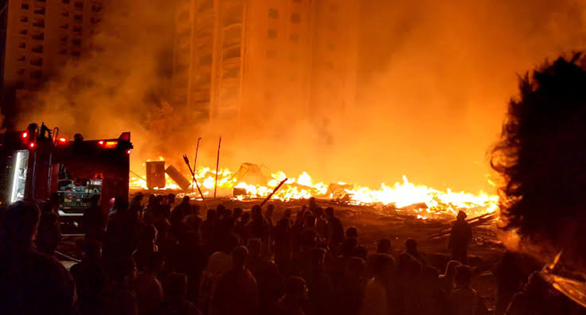 Massive fire engulfing a furniture market at night in Karachi, with crowds watching near a fire engine.