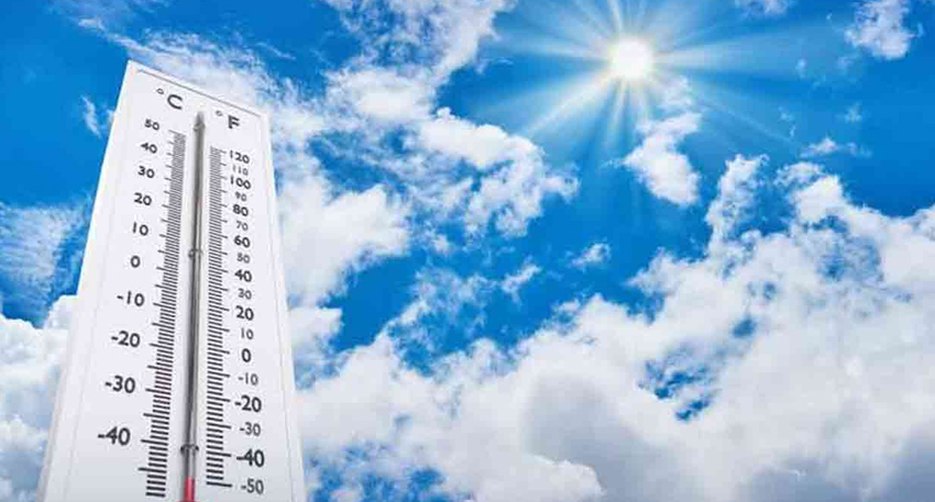 A outdoor thermometer showing temperatures against a bright sunny blue sky filled with clouds.