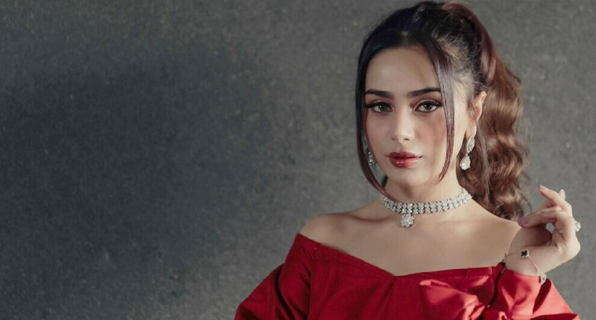 Aima Baig in a red dress wearing a silver necklace.